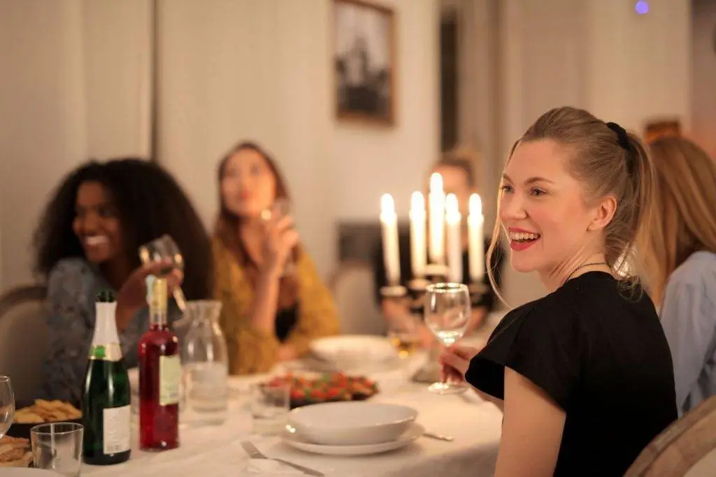 Group of diverse women enjoying a candle-lit dinner, smiling and chatting.