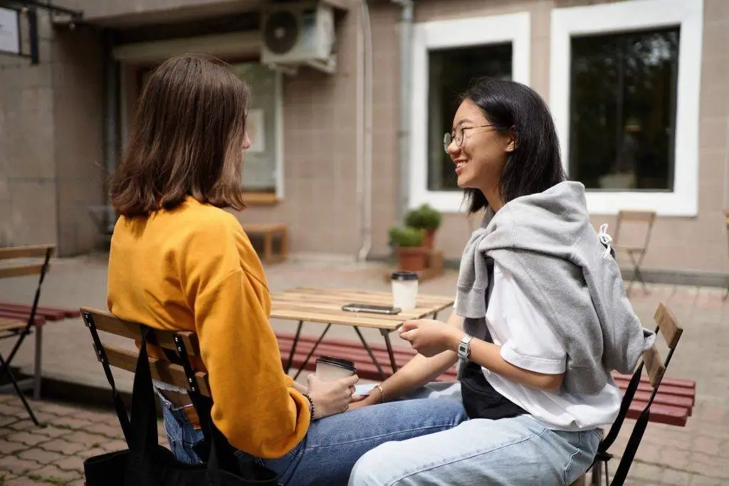 Two women enjoying a friendly chat over coffee at an outdoor café.